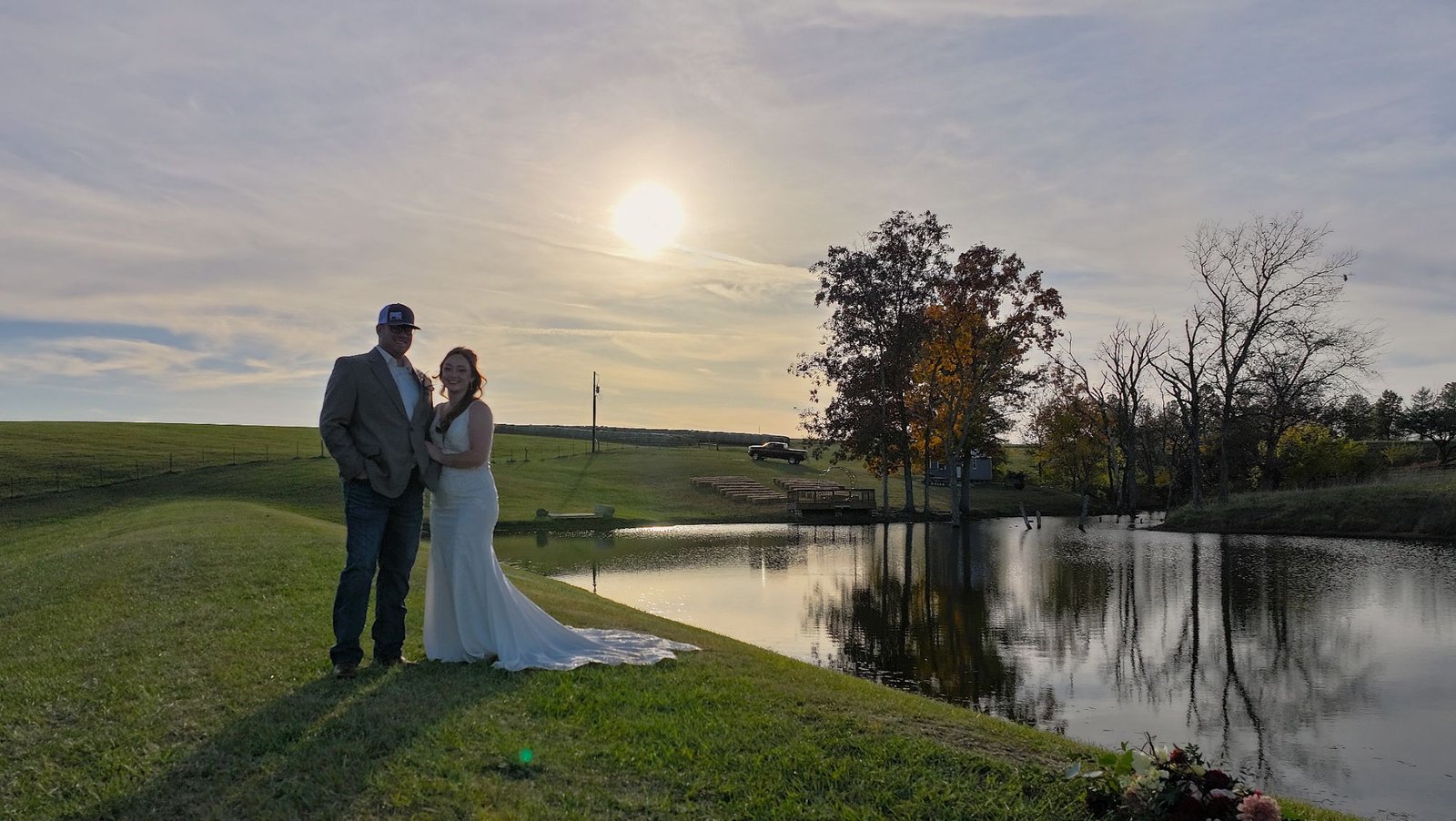 Bride and groom posing by a pond at sunset