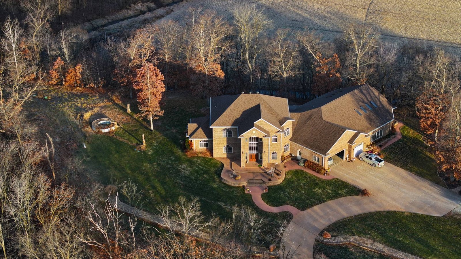 Aerial view of a large brick home surrounded by fall foliage