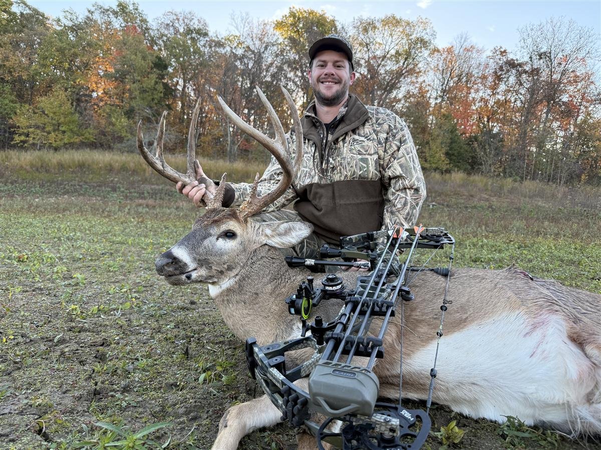 Bowhunter with a recovered buck in a fall Missouri field