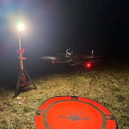 Recon1 thermal drone on a landing pad lit by a work light at night